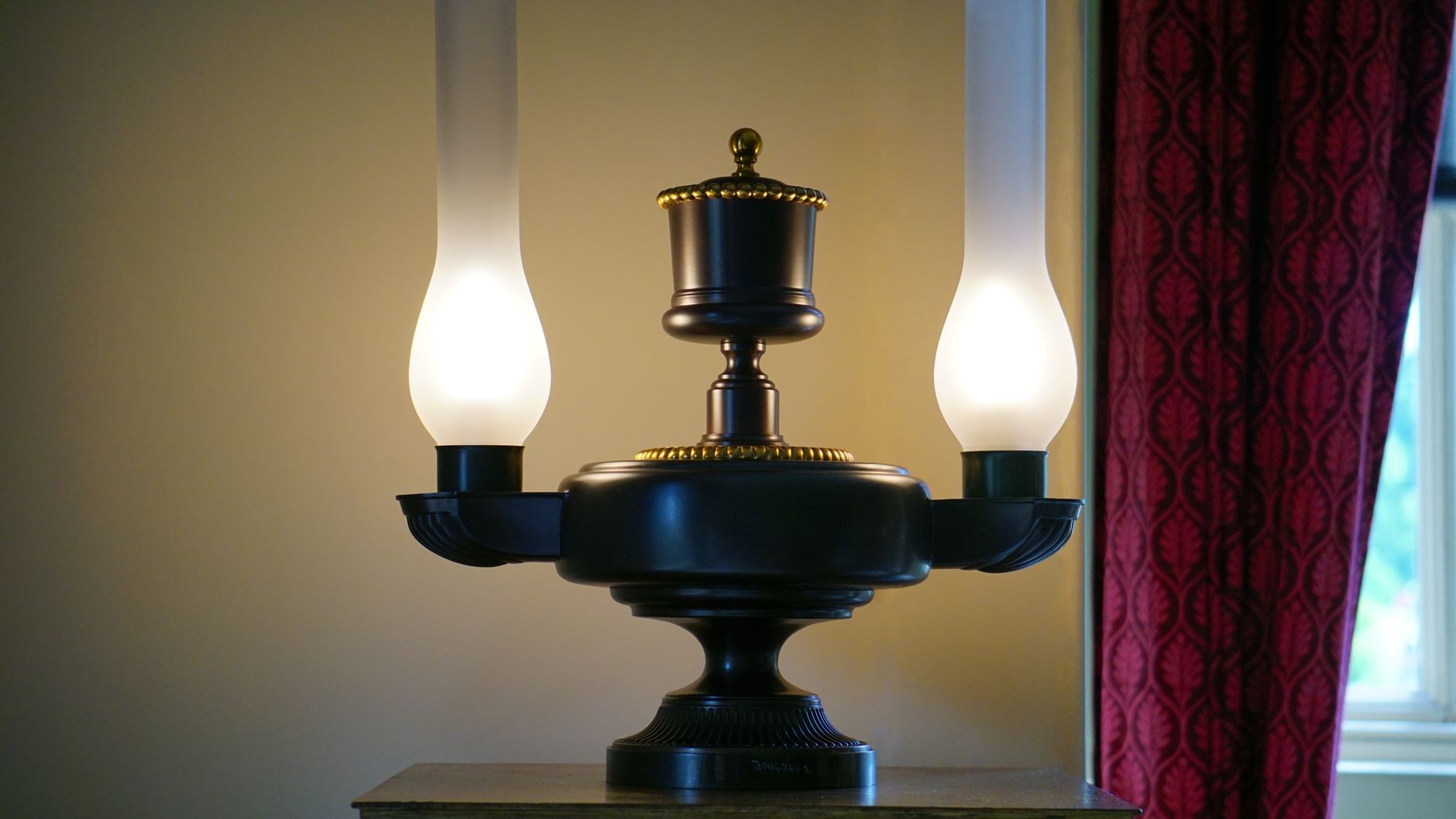 black and white table lamp beside red curtain