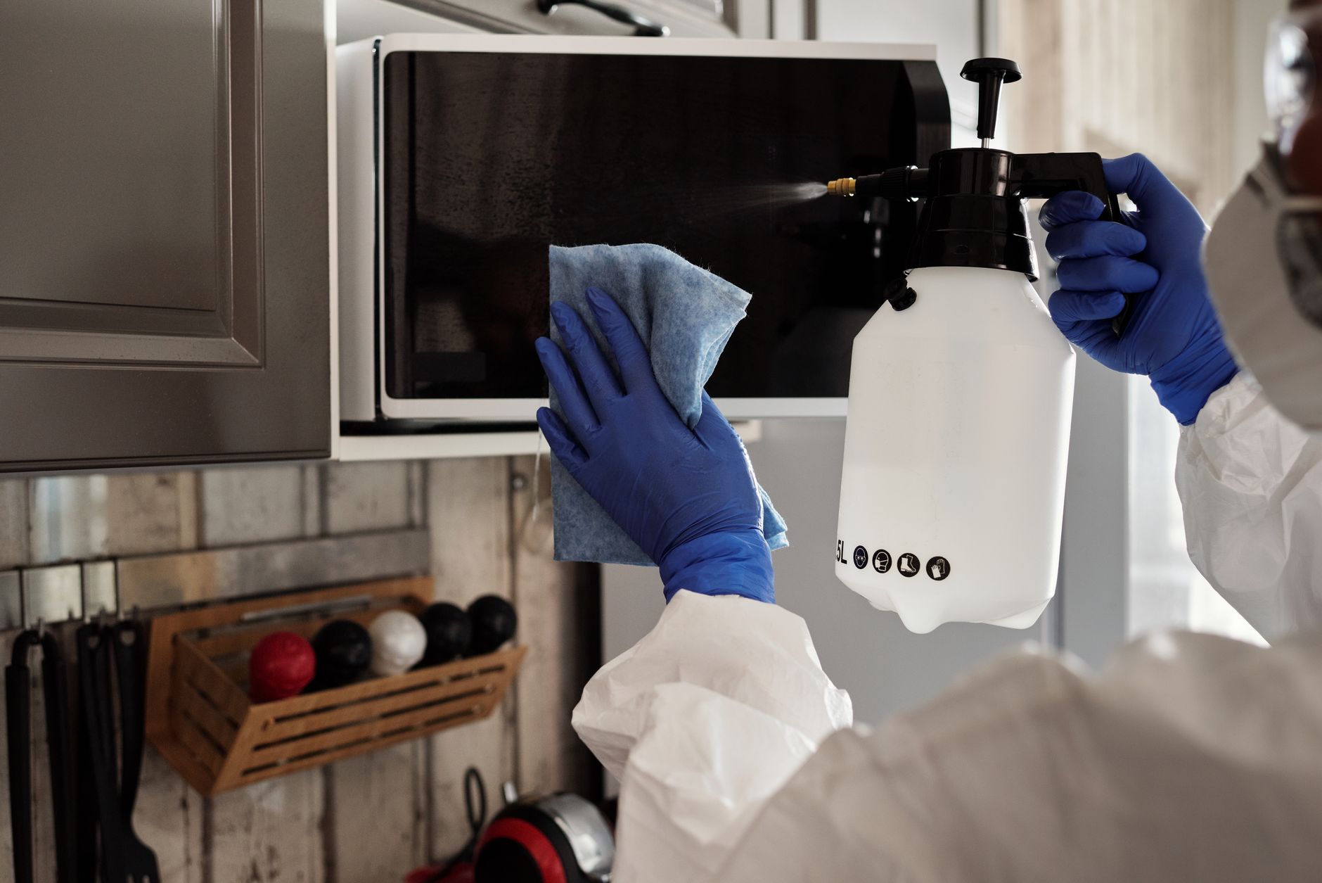 cleaner wiping microwave oven in kitchen