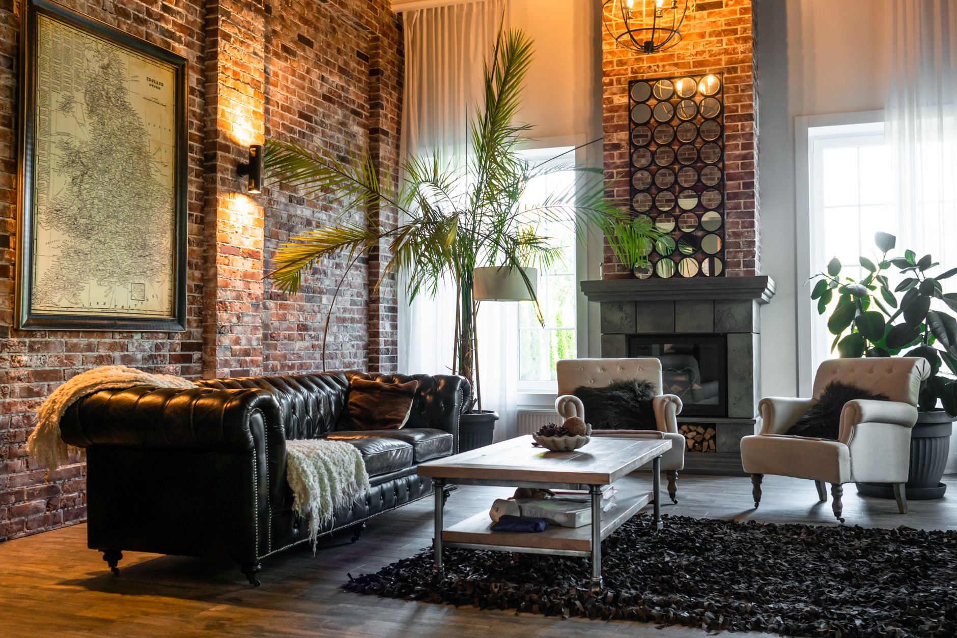 living room with green plants and brown sofa chairs