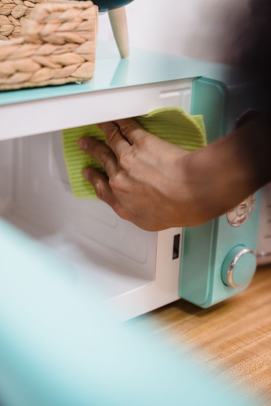 a person cleaning a microwave oven