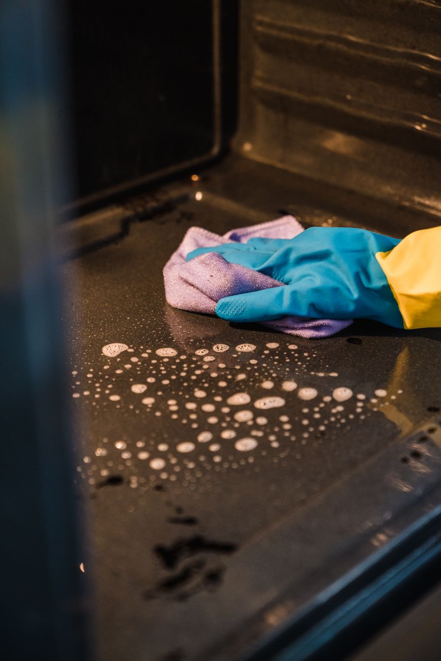 hand in rubber glove cleaning oven surface