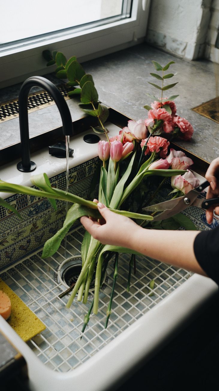 woman cutting bouquet from clove flowers and tulips in sink