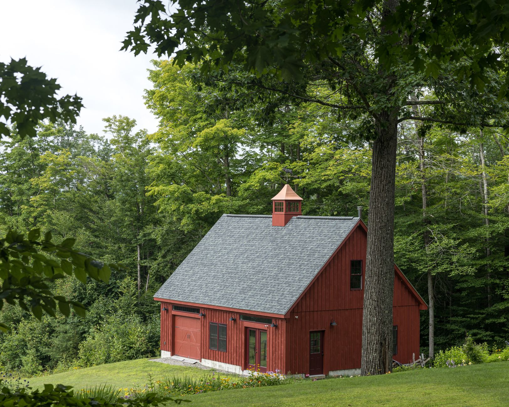 a red barn sits in the middle of a lush green field