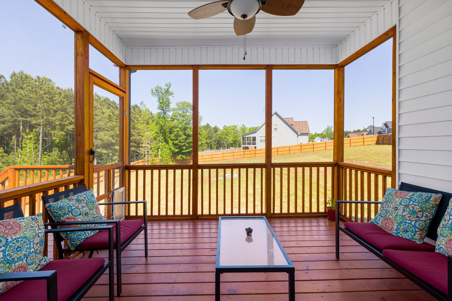 an enclosed wooden porch with red and blue cushions